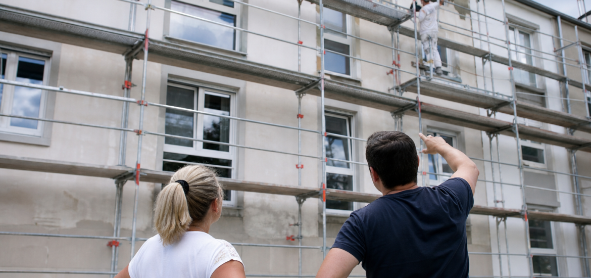 Deux personnes regardant façade d'immeuble avec échafaudage et ouvrier